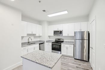 A kitchen with white cabinets and a granite countertop.